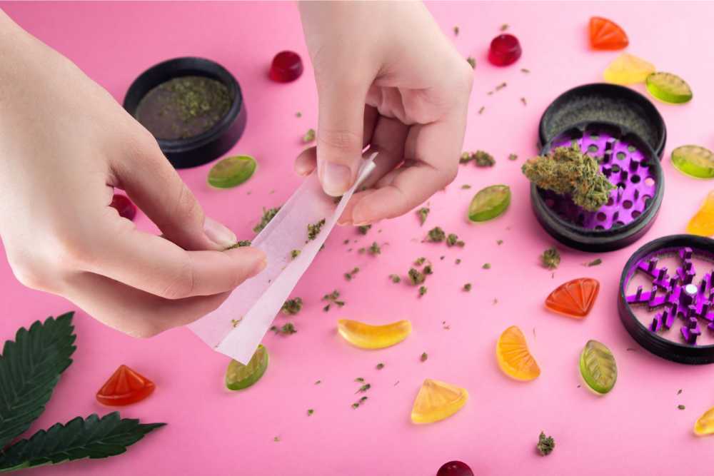 making cannabis joint with gummies in background