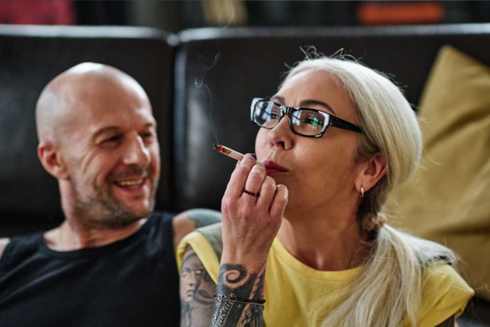 mature woman tatted arm eyeglasses smoking cannabis