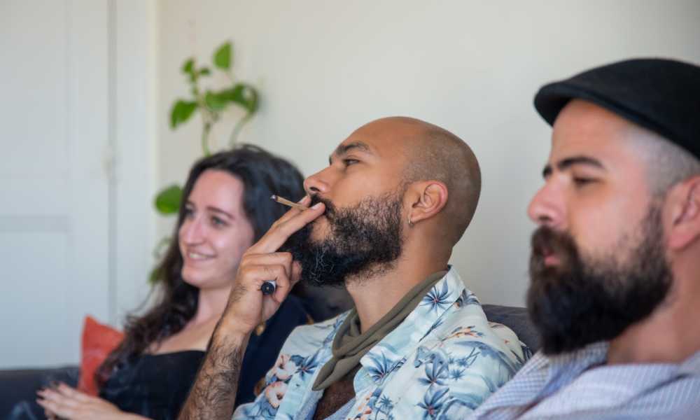 three people enjoying cannabis one man smoking joint