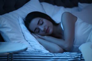 woman sleeping in bed bathed in blue light