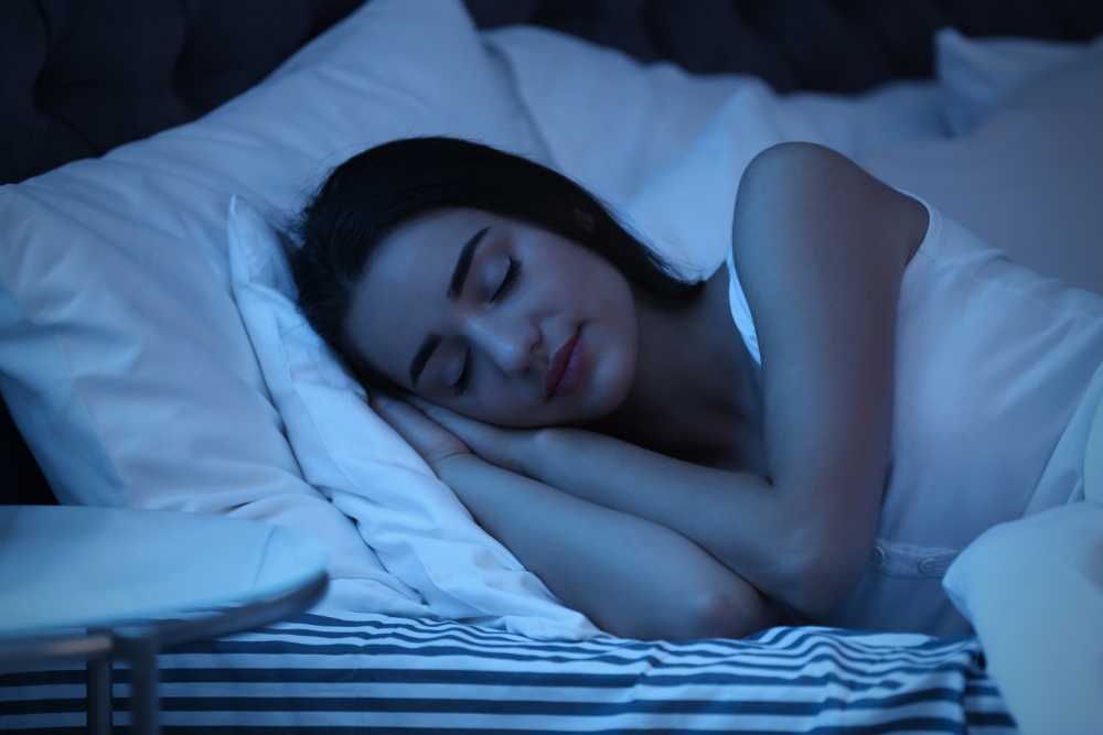 woman sleeping in bed bathed in blue light