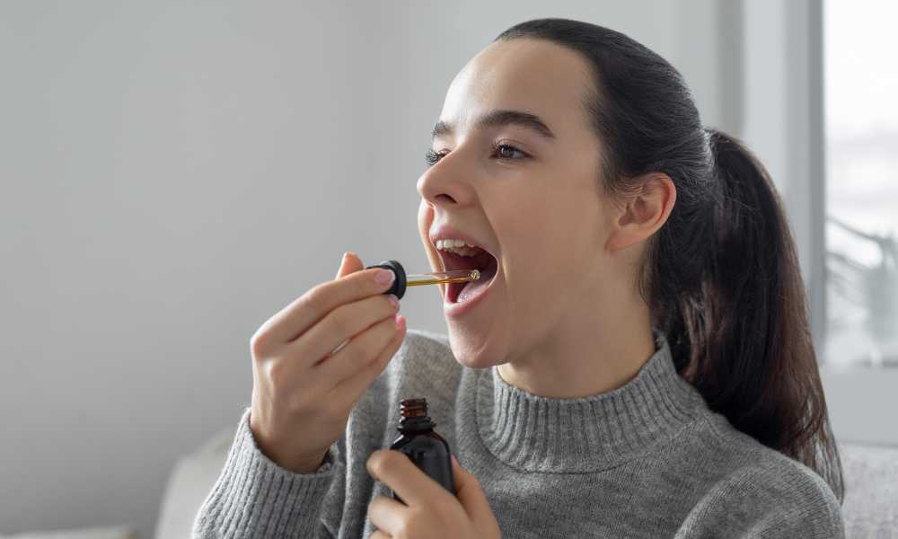 woman taking cbd oil using dropper top