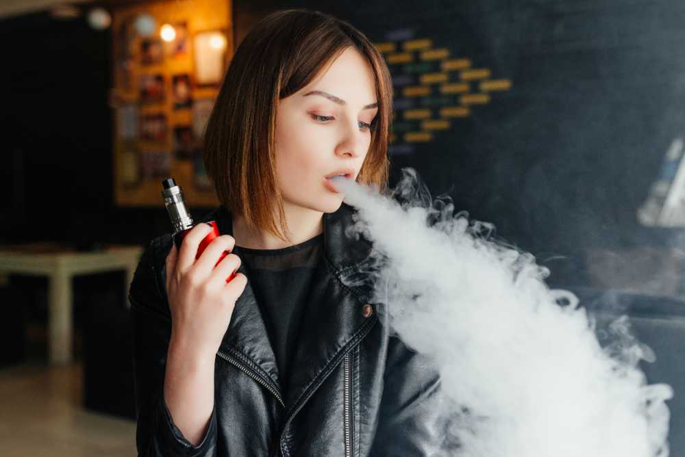 young woman with short hair exhaling thick vape smoke