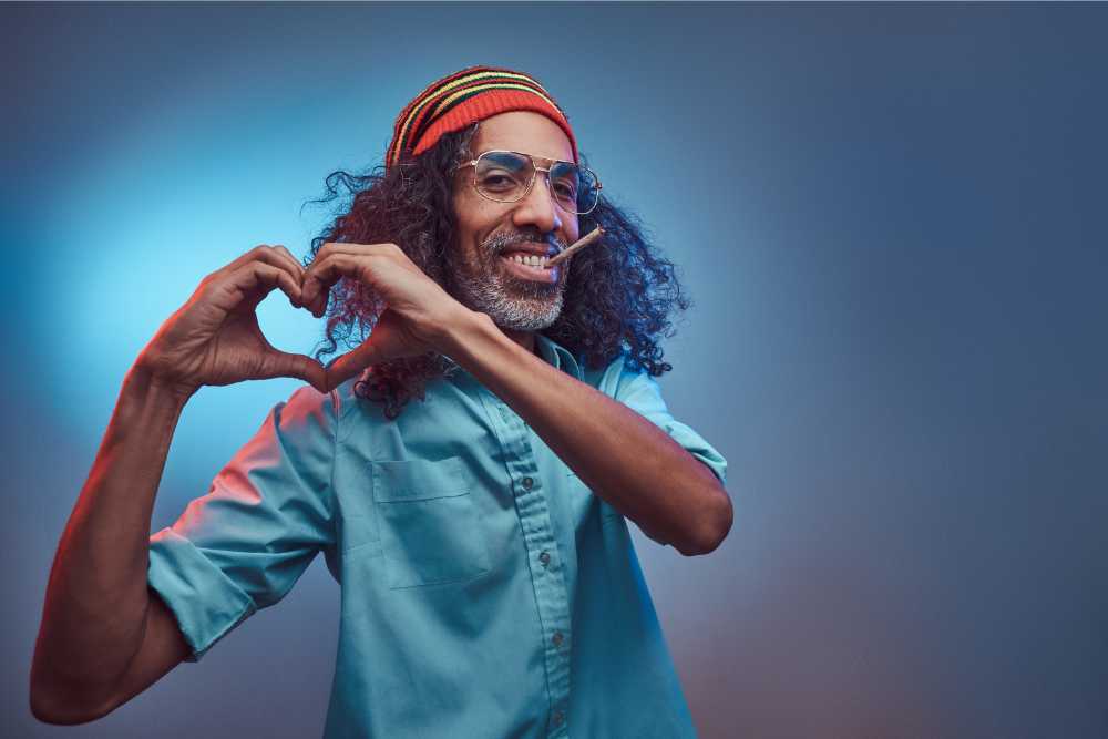 happy man wearing beanie smoking joint making heart hands