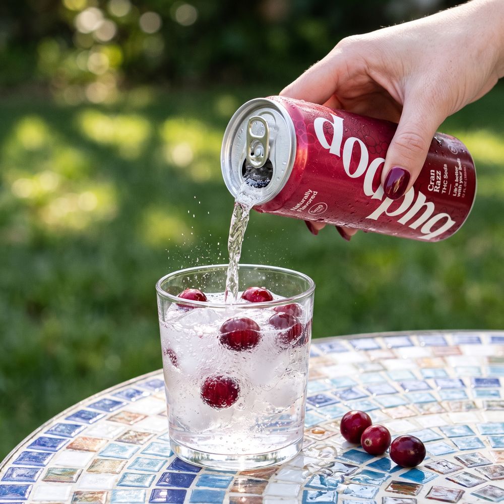 closeup shot of woman pouring budpop cran razz thc soda into cup